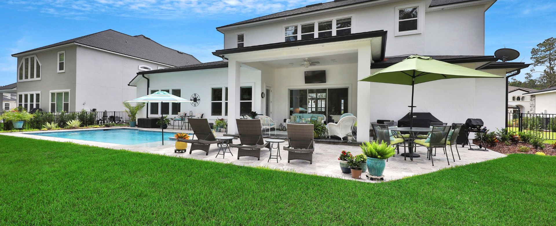 A large white house with a swimming pool and patio furniture.