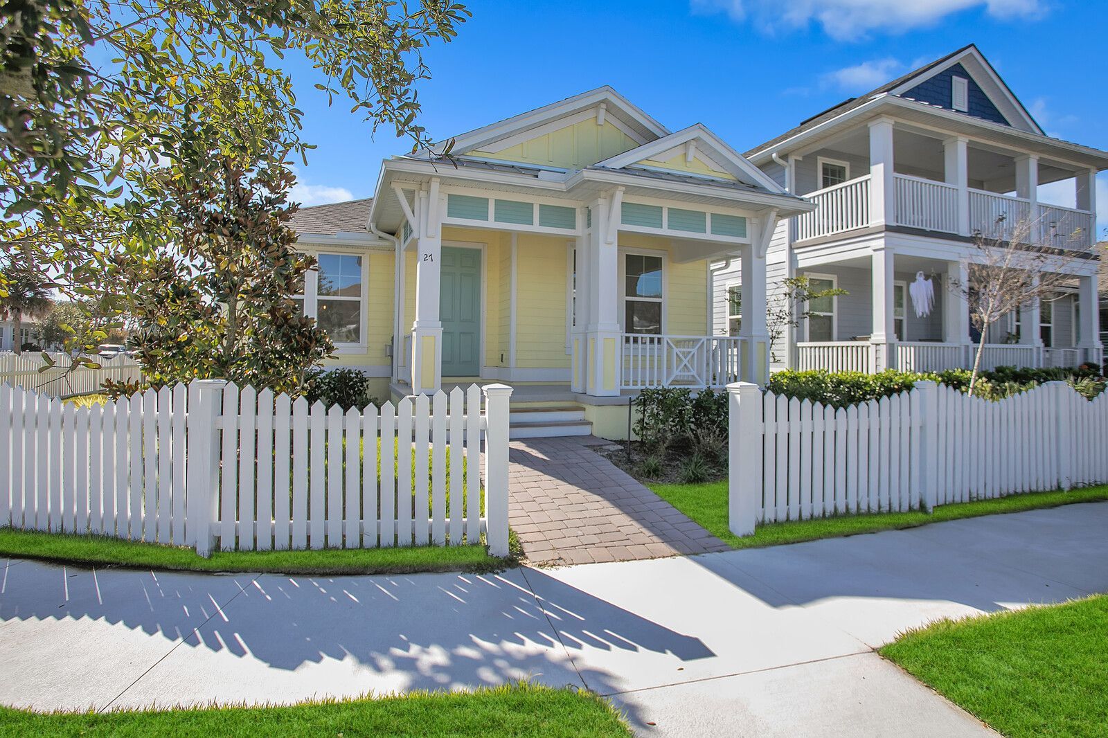 A yellow house with a white picket fence in front of it.