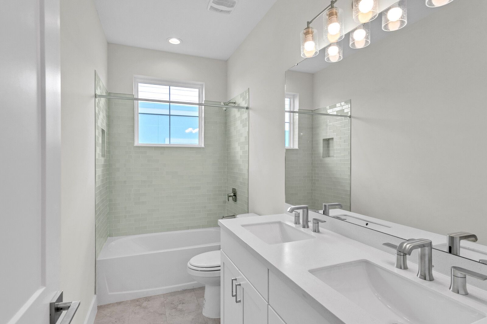 A bathroom with two sinks , a toilet , and a window.