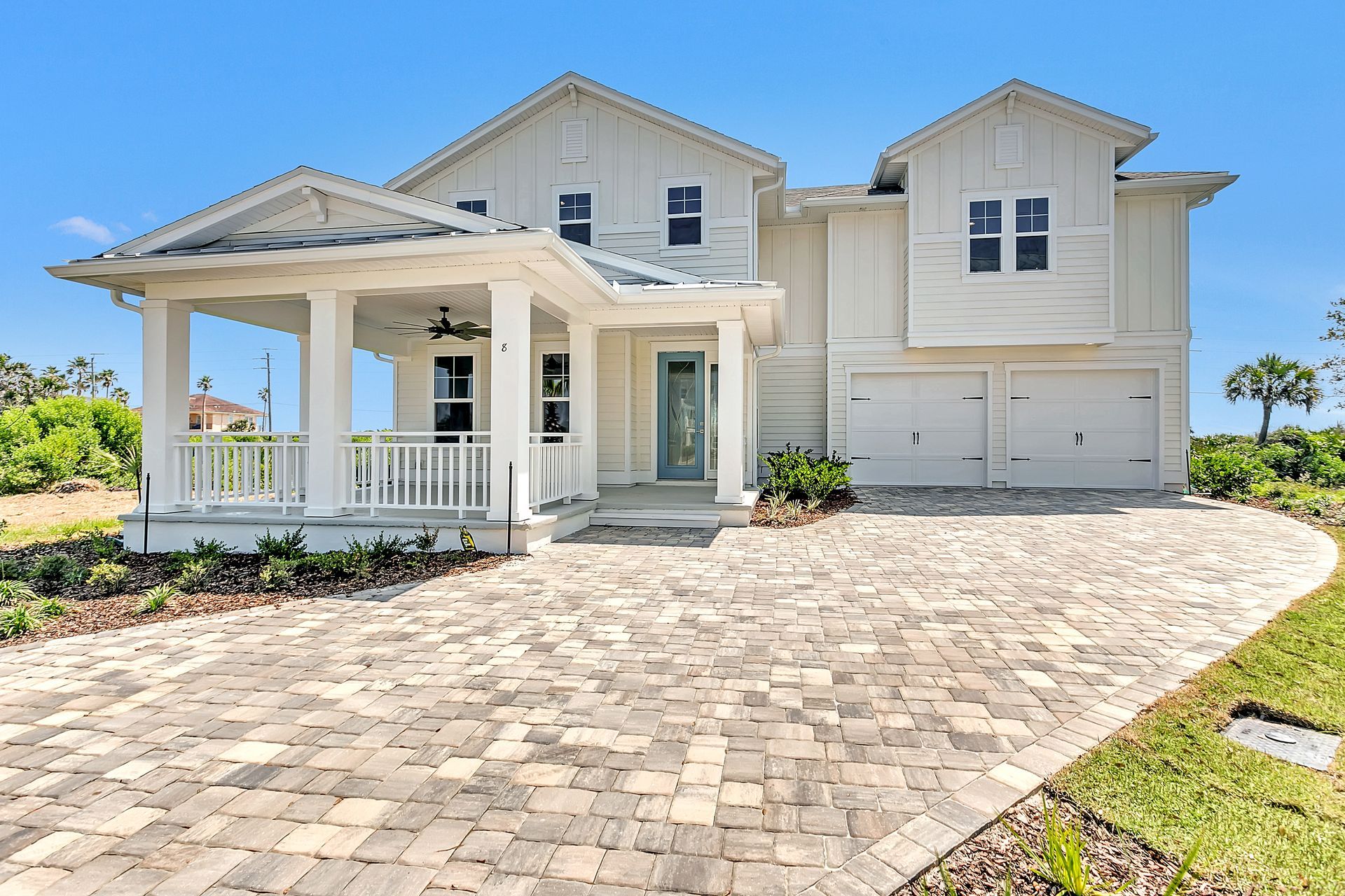 A large white house with a brick driveway and porch.