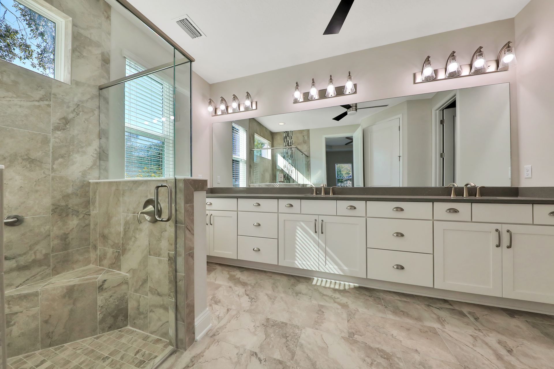A bathroom with two sinks and a walk in shower.