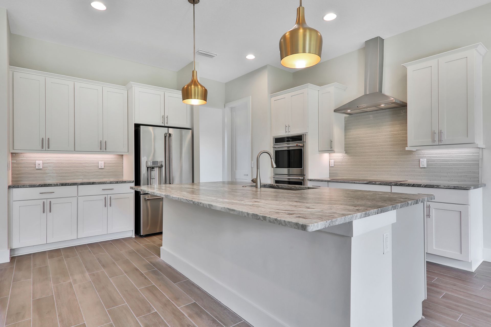A kitchen with white cabinets , granite counter tops , stainless steel appliances and a large island.