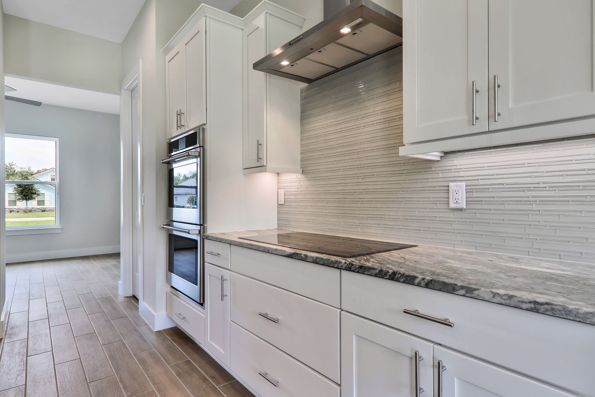 A kitchen with white cabinets , granite counter tops and stainless steel appliances.