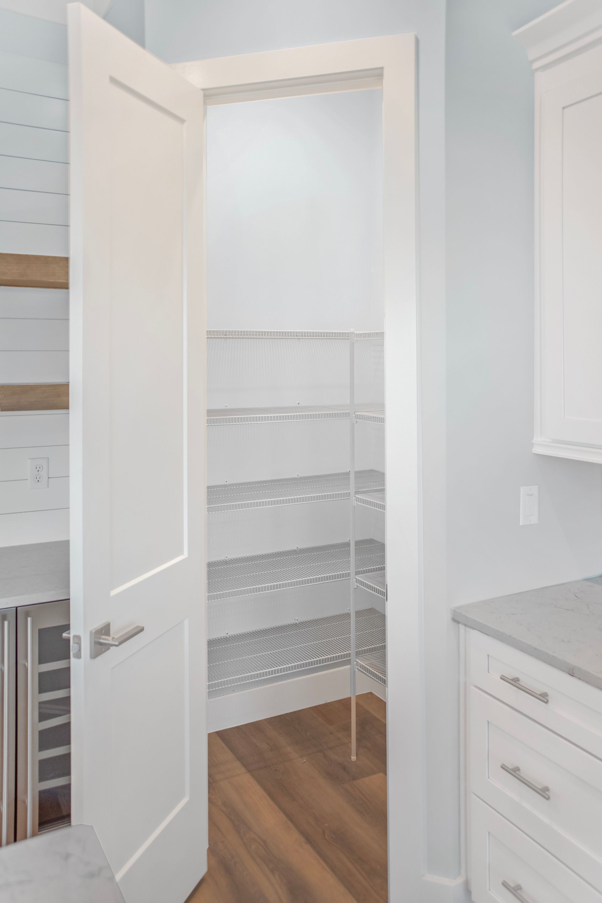 A pantry with a door open and shelves in a kitchen.