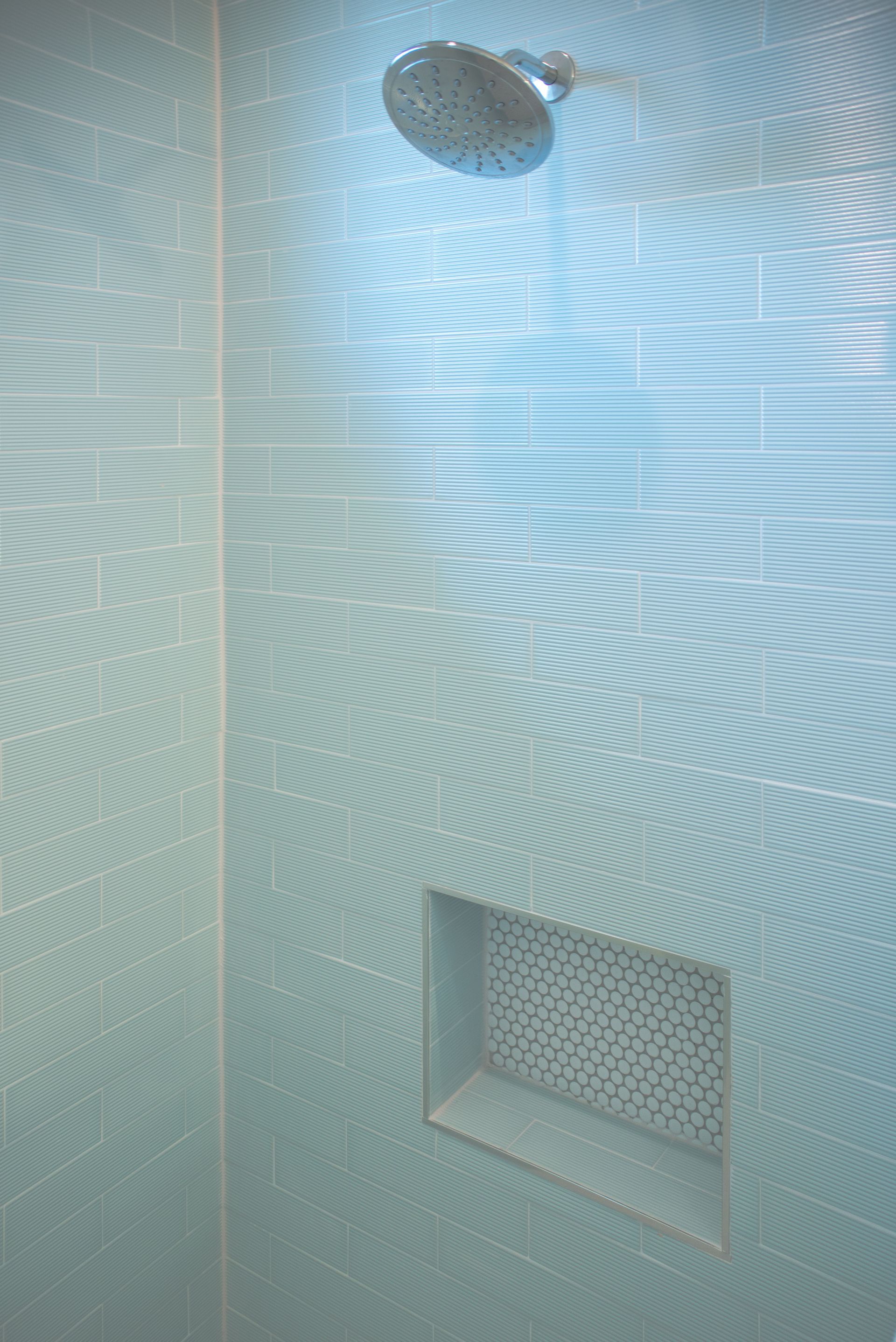 A shower head is hanging from the ceiling of a bathroom.