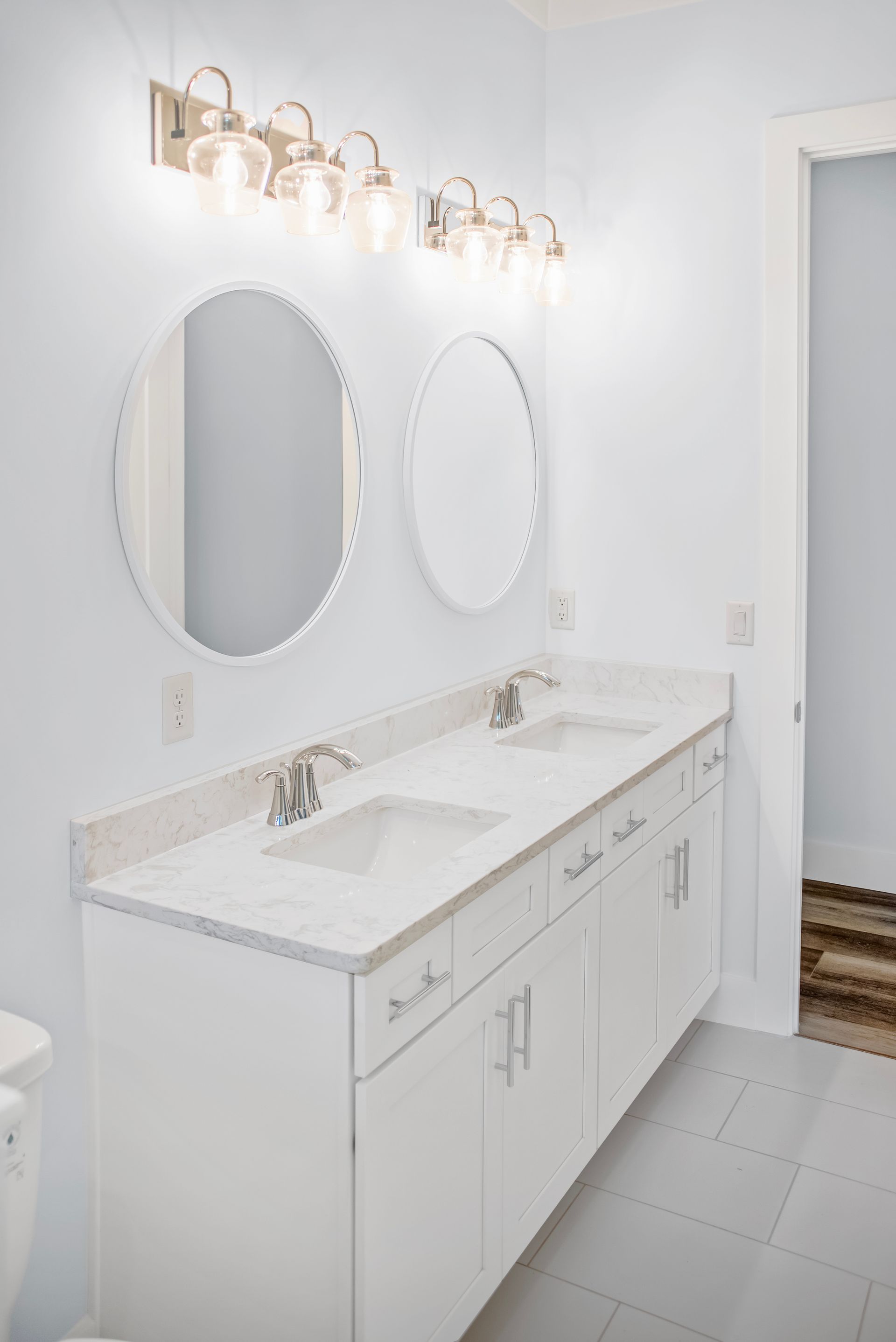 A bathroom with two sinks , two mirrors , and a toilet.