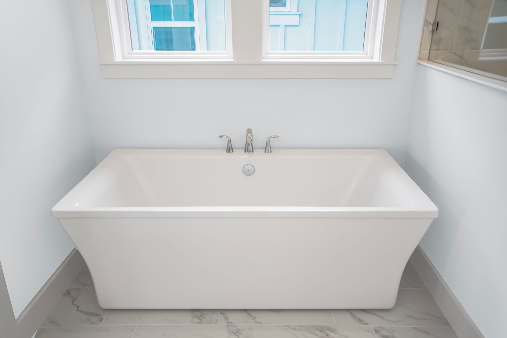 A white bathtub is sitting in a bathroom next to a window.