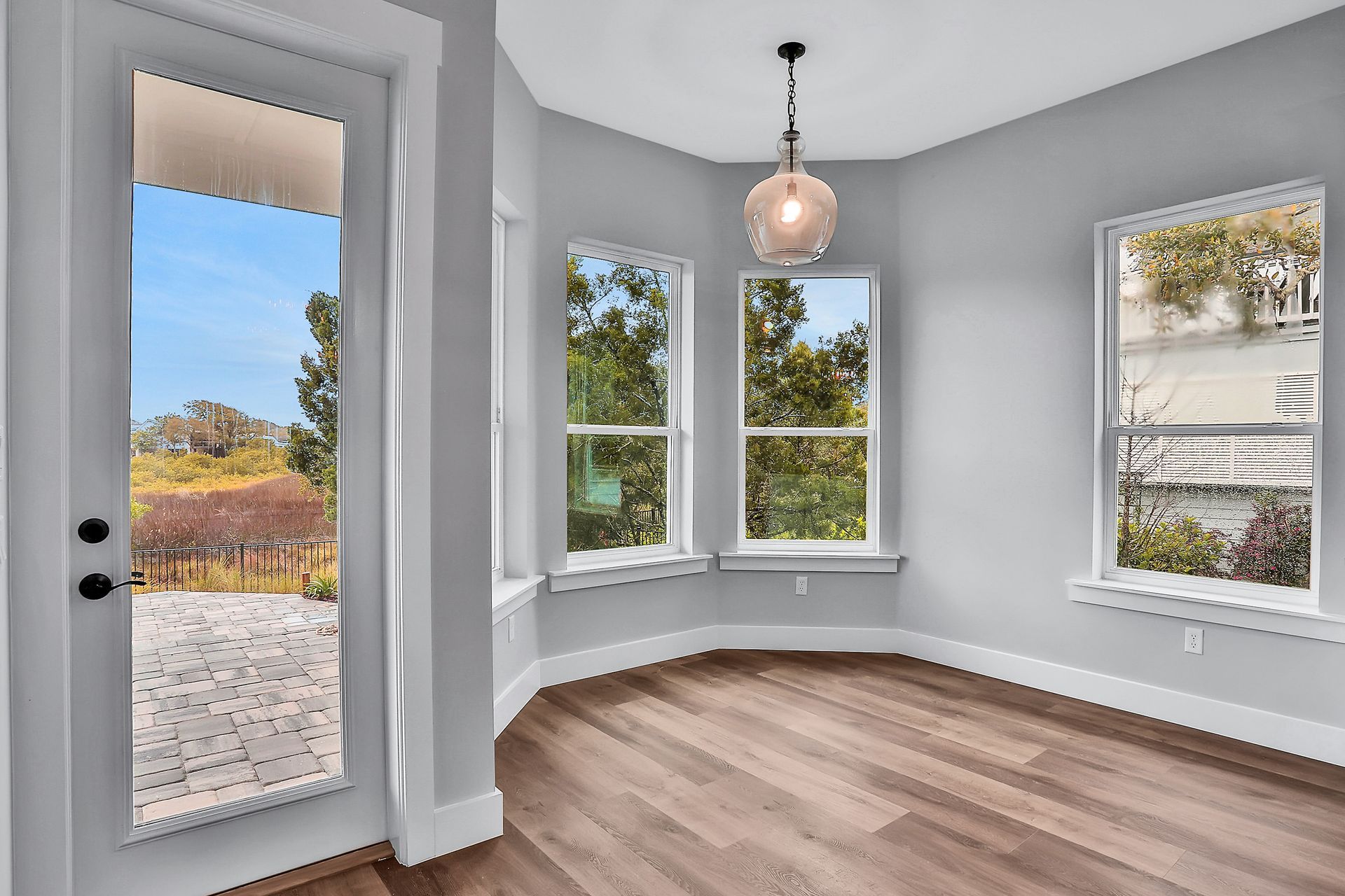 An empty room with hardwood floors and a sliding glass door.