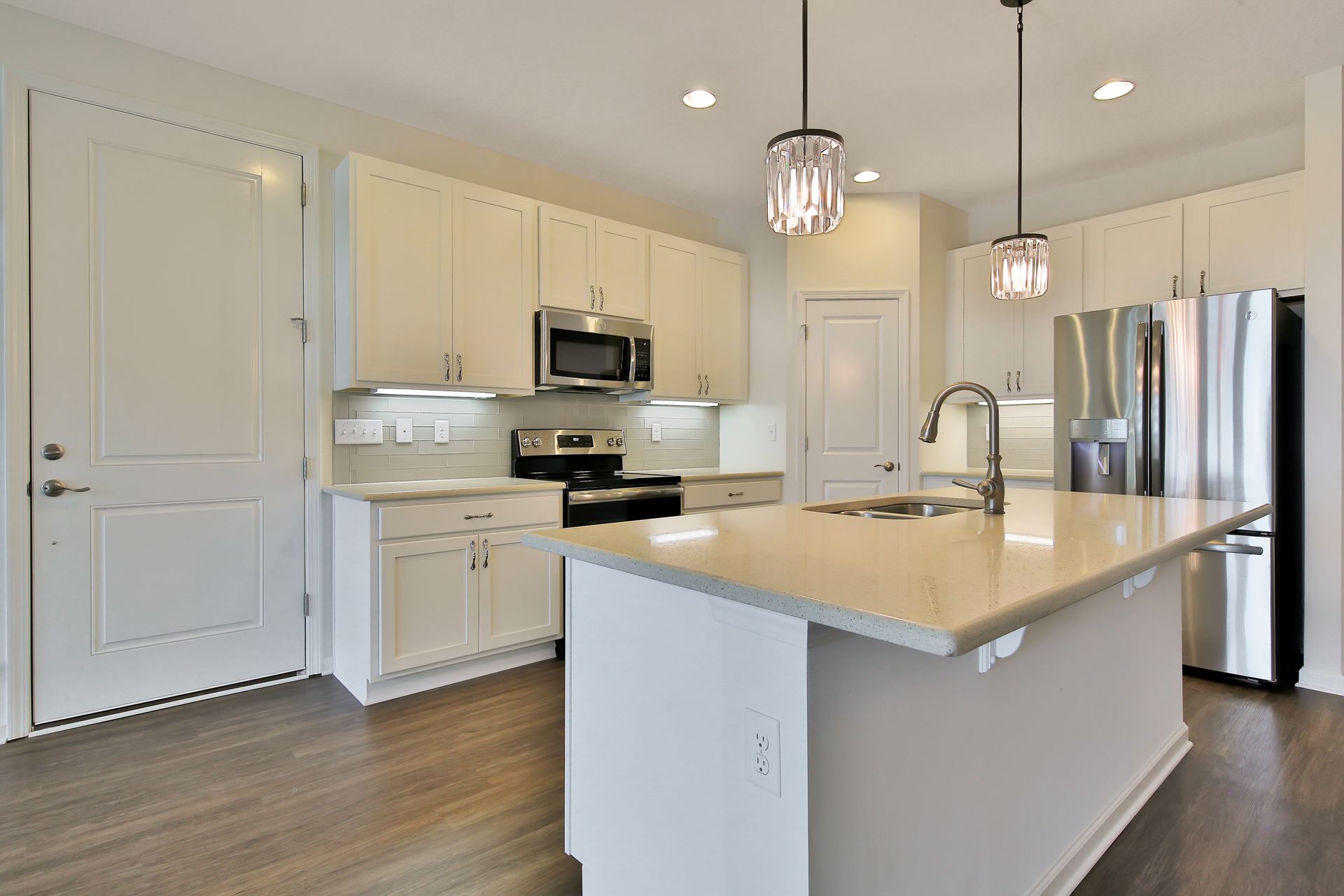 A kitchen with white cabinets , stainless steel appliances , and a large island.