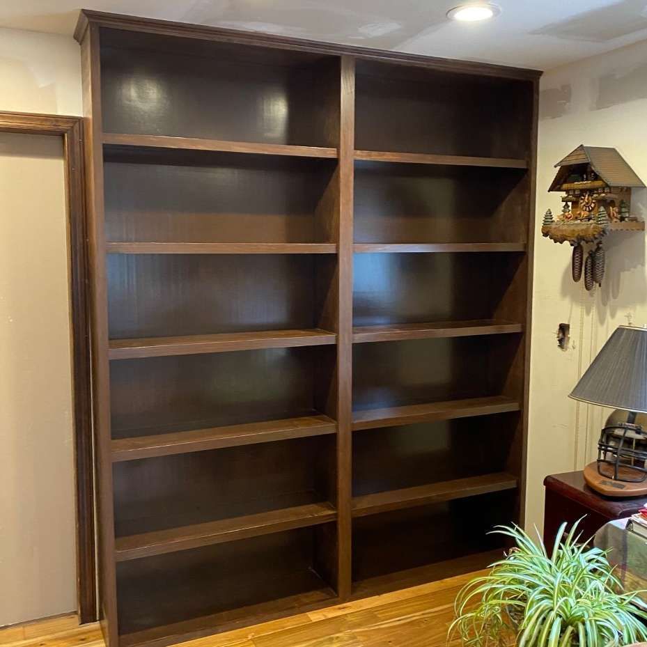 Two tall, dark wooden bookshelves, empty, against a light wall.