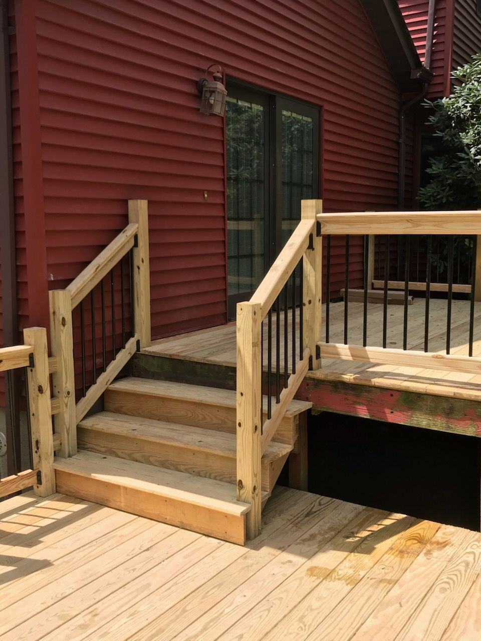 Wooden deck with stairs leading to a red house.