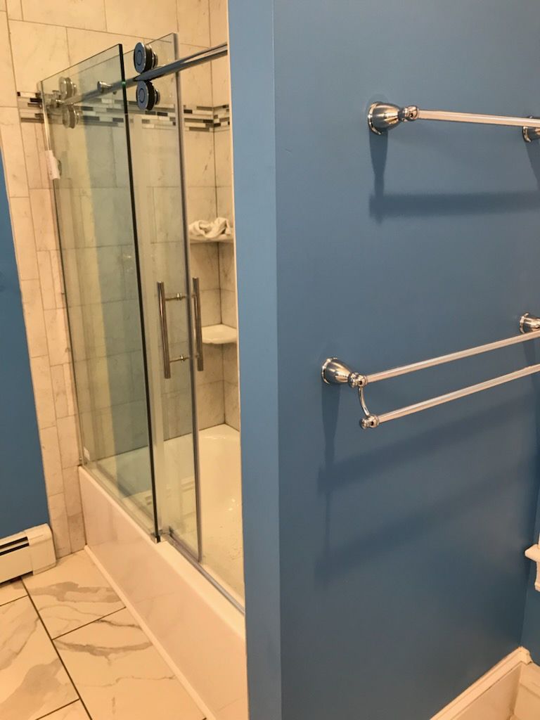 Bathroom interior with a glass shower, blue walls, and towel racks.