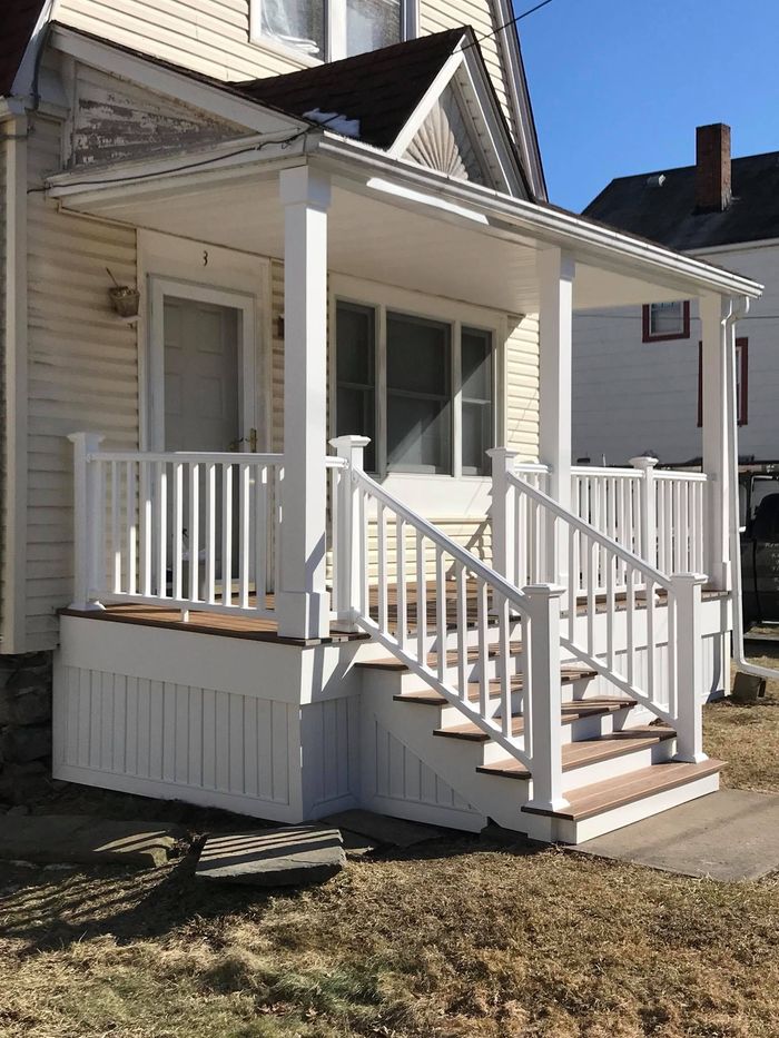White porch with stairs on a two-story house with a tan exterior.