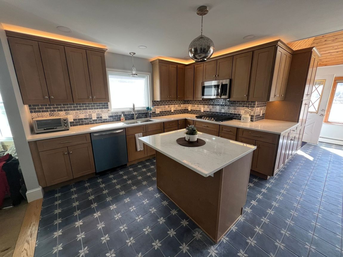 Kitchen with wooden cabinets, blue patterned floor, island, and stainless steel appliances.