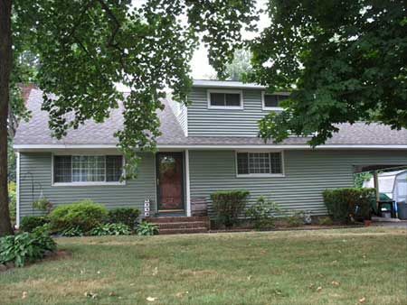 Green house with front yard and trees.
