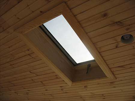 Skylight in wooden ceiling, framed with light-colored wood.