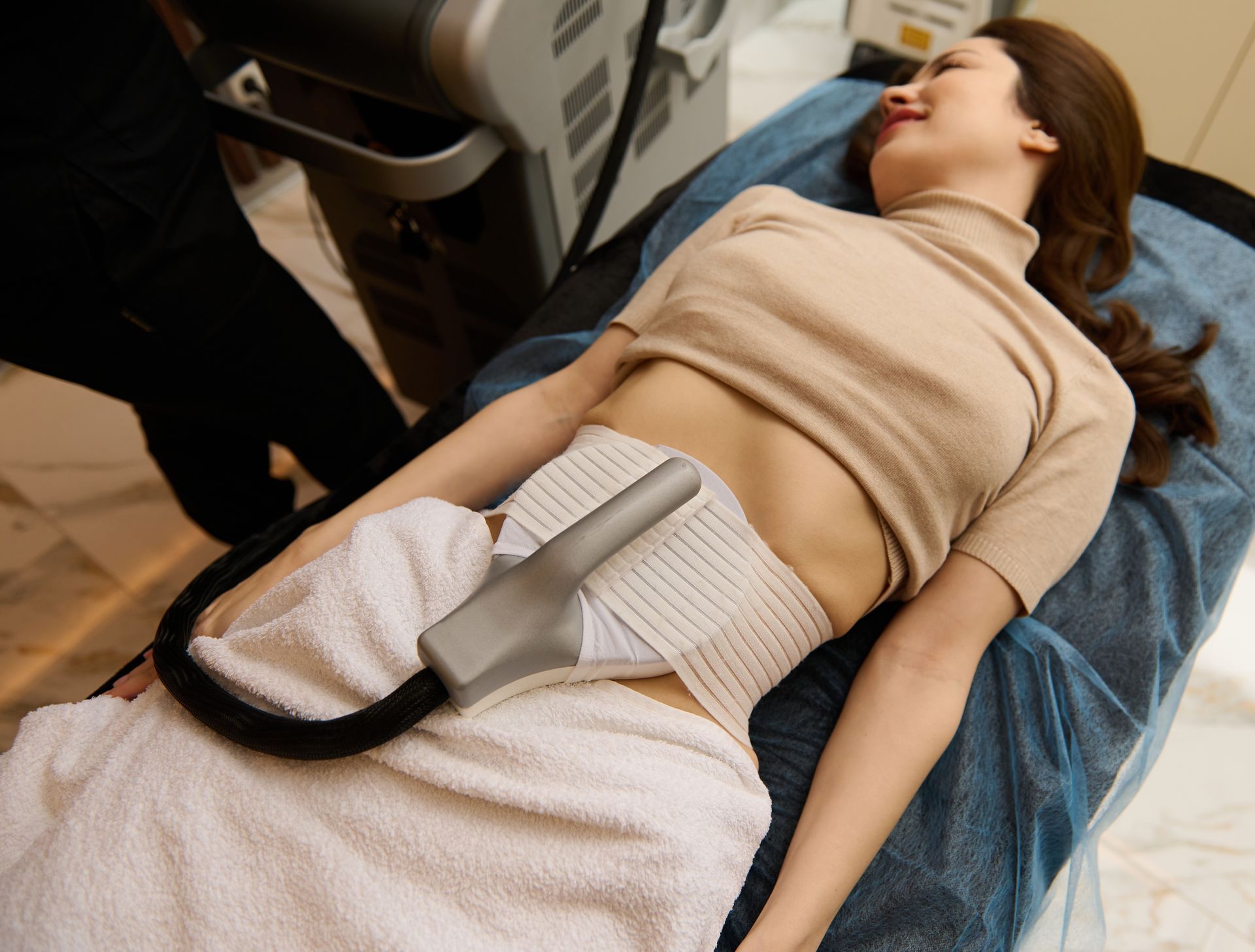 Woman undergoing a body contouring procedure on her abdomen with a cooling device.