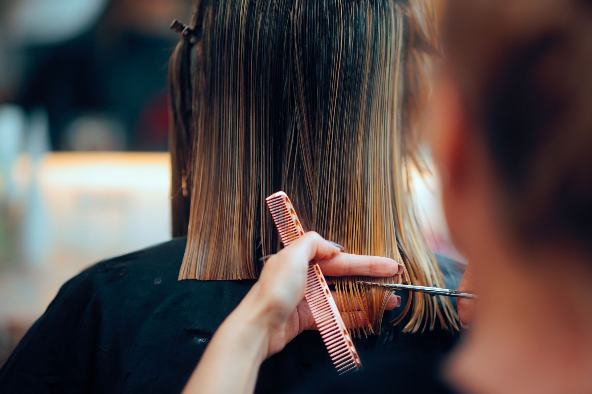 A person in a salon getting their hair styled with highlights.