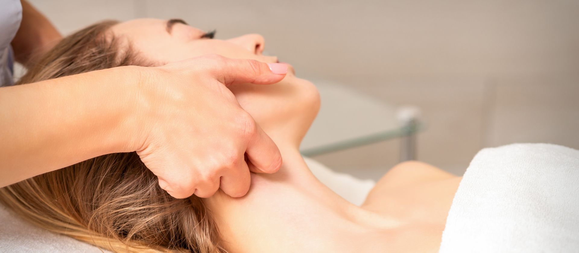 Person's leg receiving massage on a white surface; hands massaging calf muscle.