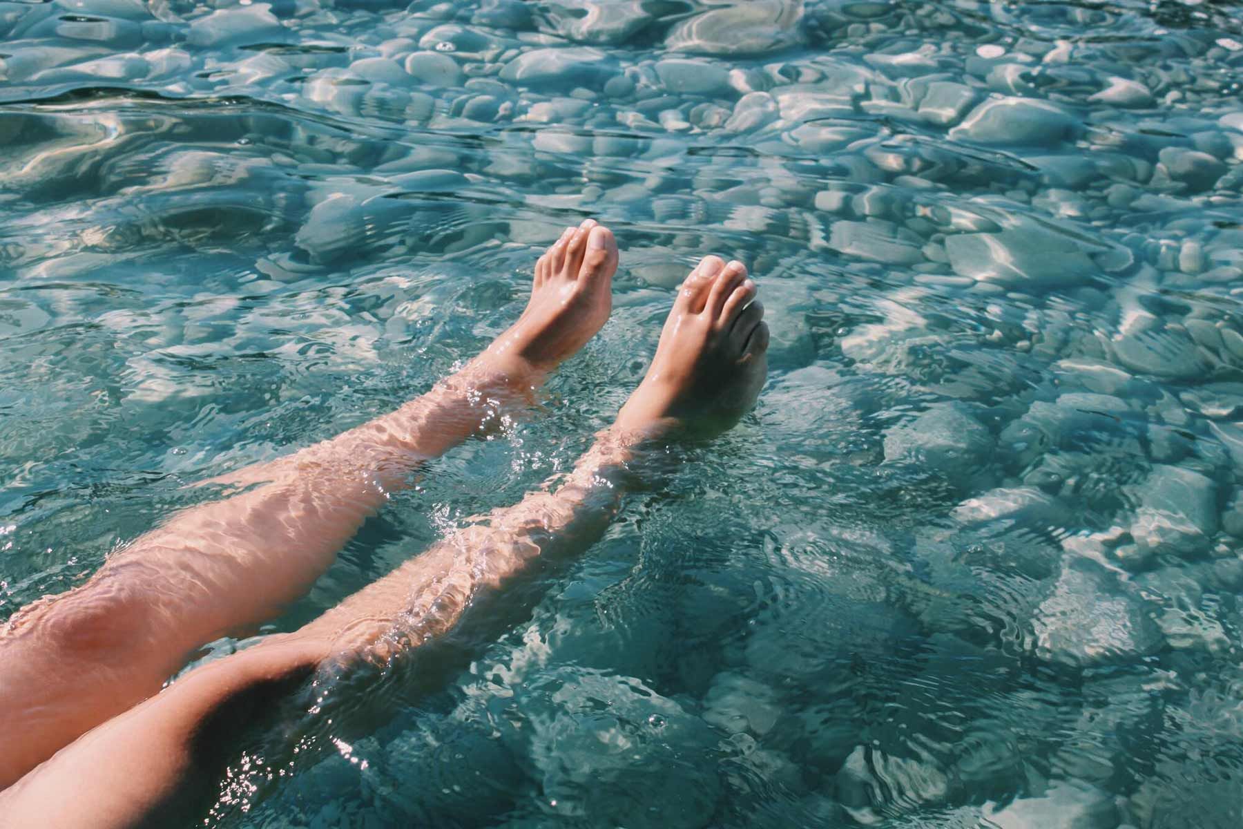 A Person Is Laying In The Water With Their Feet In The Water — Sandy Gugenberger Podiatrist in Port Macquarie, NSW