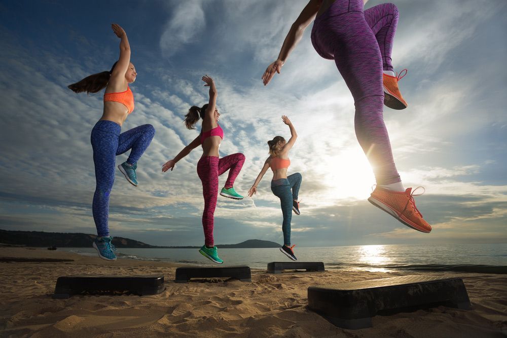 A Group Of Women Are Jumping In The Air On A Beach — Sandy Gugenberger Podiatrist in Port Macquarie, NSW