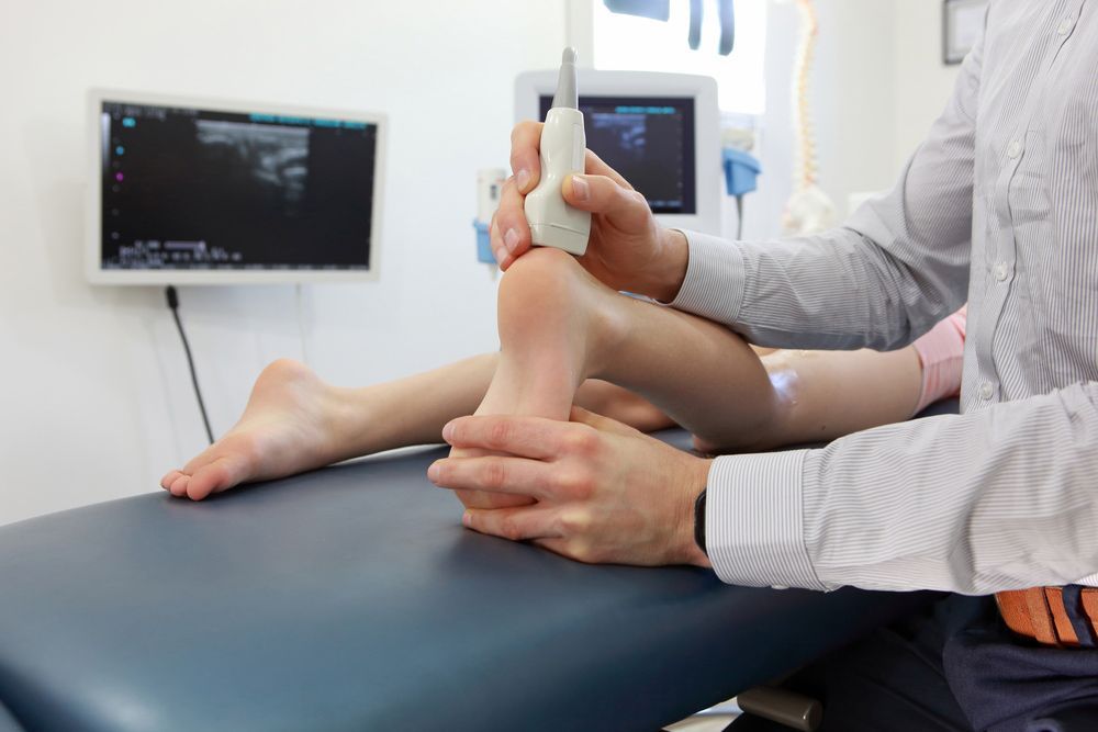 A Doctor Is Examining A Child's Foot With An Ultrasound Machine — Sandy Gugenberger Podiatrist in Port Macquarie, NSW