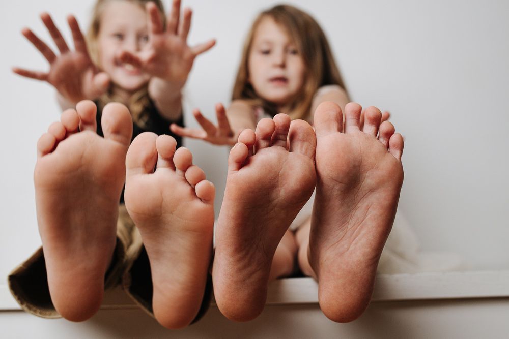 Two Little Girls Are Sitting Next To Each Other With Their Feet Up — Sandy Gugenberger Podiatrist in Port Macquarie, NSW