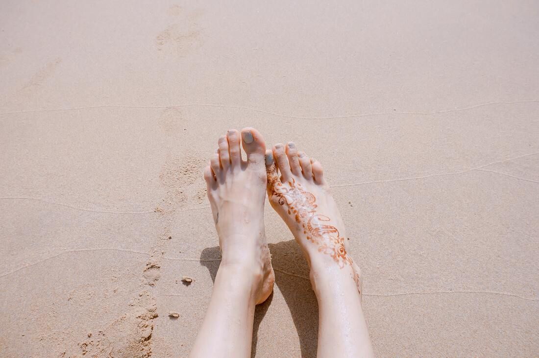 A Woman's Feet Are Standing On A Sandy Beach — Sandy Gugenberger Podiatrist in Port Macquarie, NSW