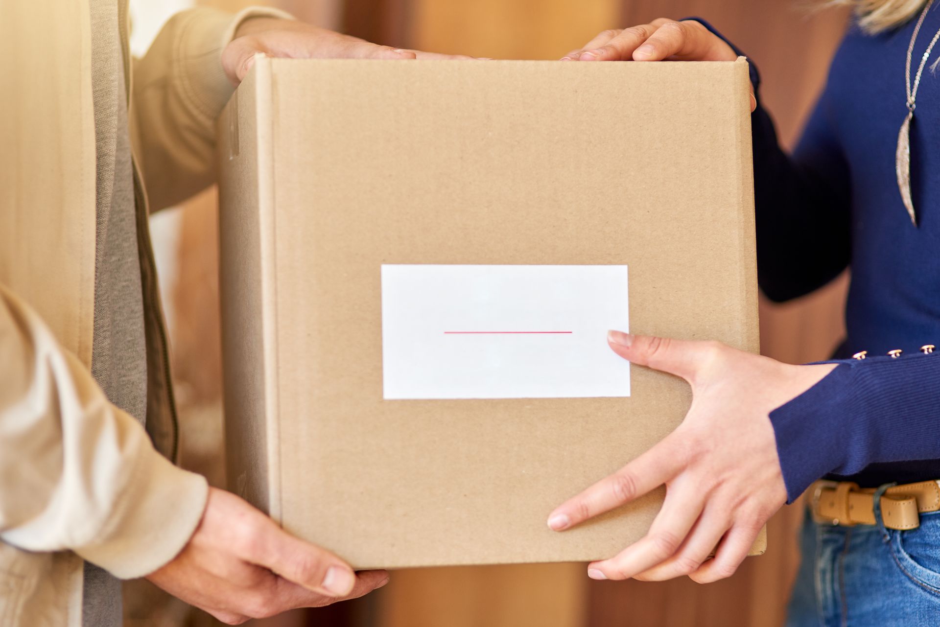 A woman is handing a cardboard box to another woman.