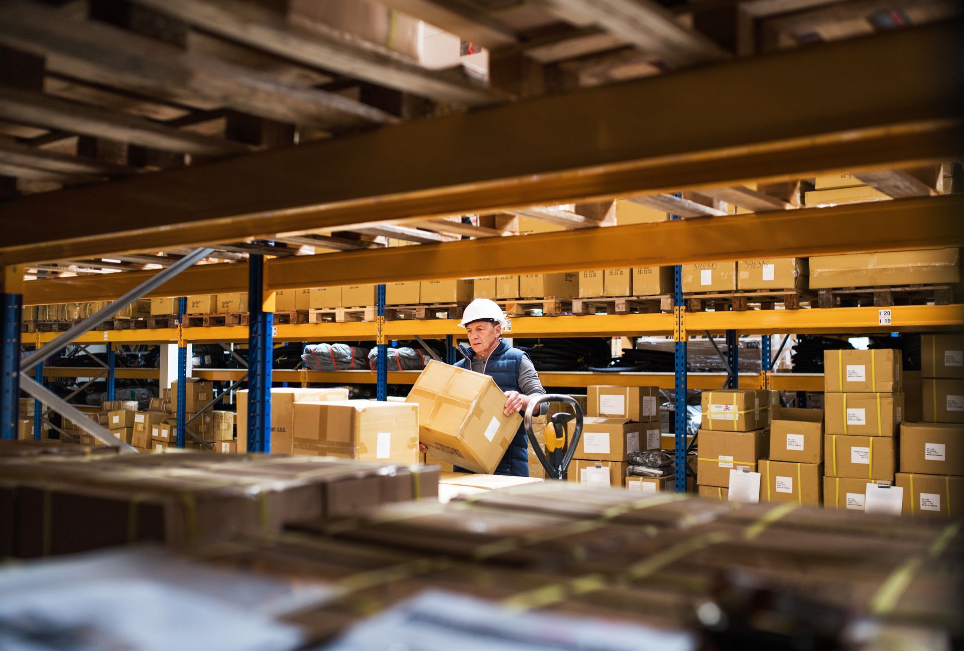 A man is carrying a box in a warehouse.