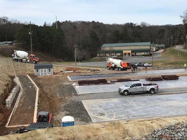 A truck is driving down a dirt road next to a cement truck.