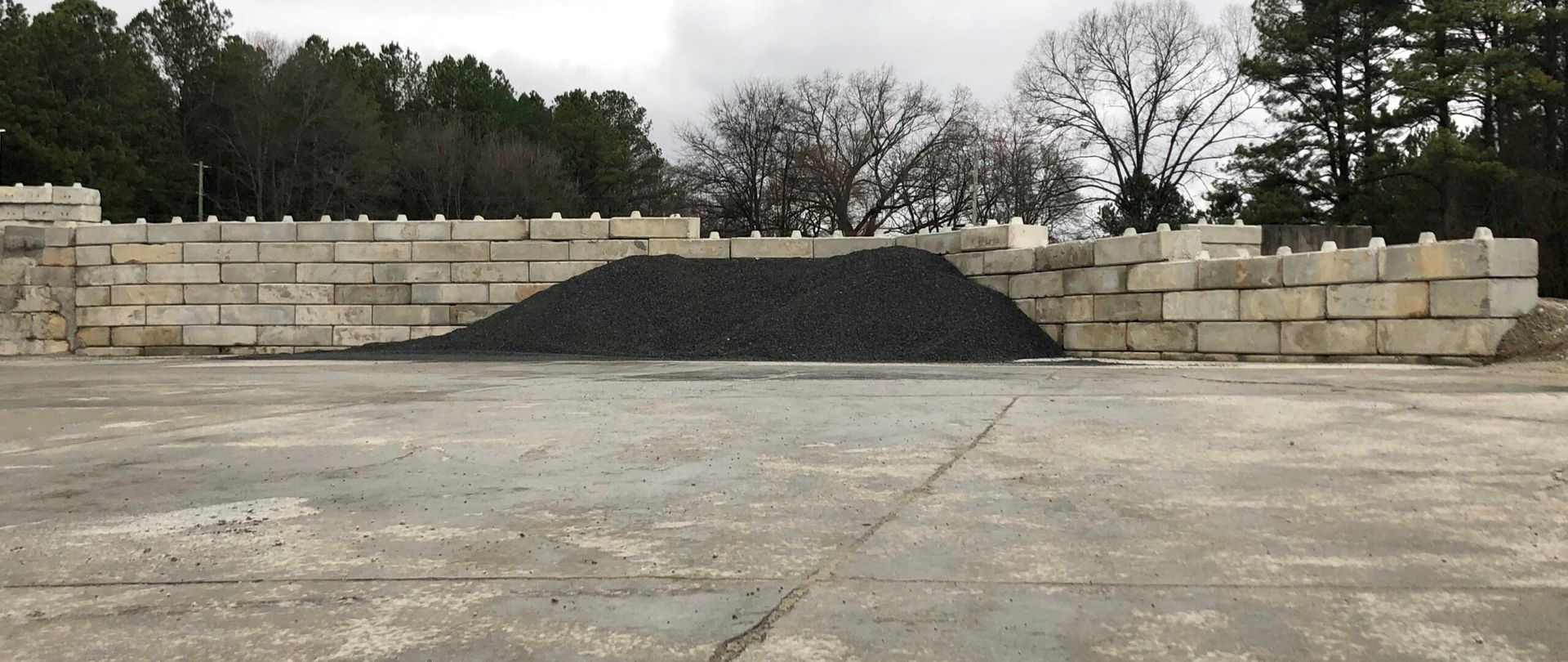 A large pile of gravel is sitting in front of a brick wall.