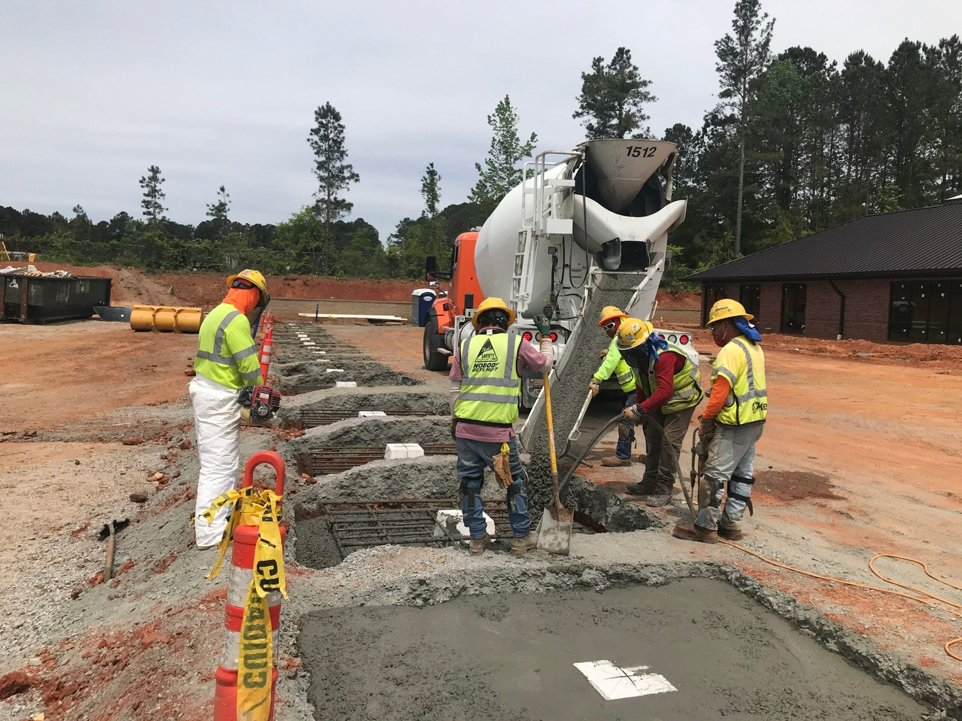 A group of construction workers are pouring concrete into a hole.