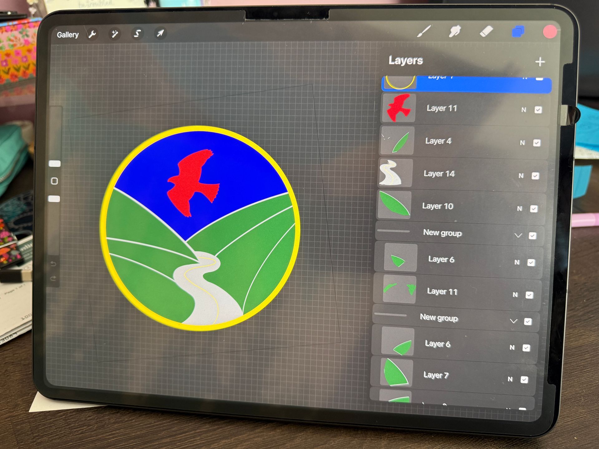 Tablet screen showing a colorful landscape logo being edited in a drawing app