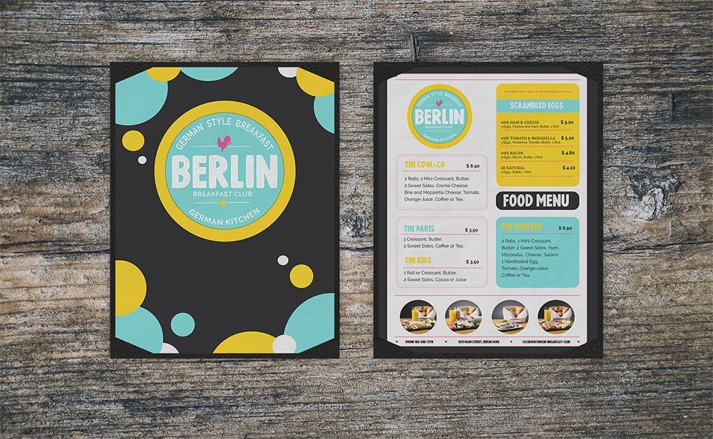 Berlin-themed menu with black cover and colorful accents, shown front and back on a gray wood table