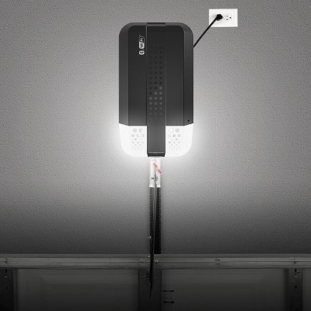 Black garage door opener with attached light, plugged into a wall outlet.