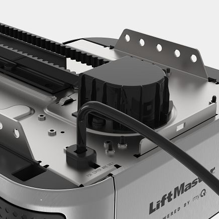 A close-up of a LiftMaster garage door opener, showing the motor housing, track, and power cord.