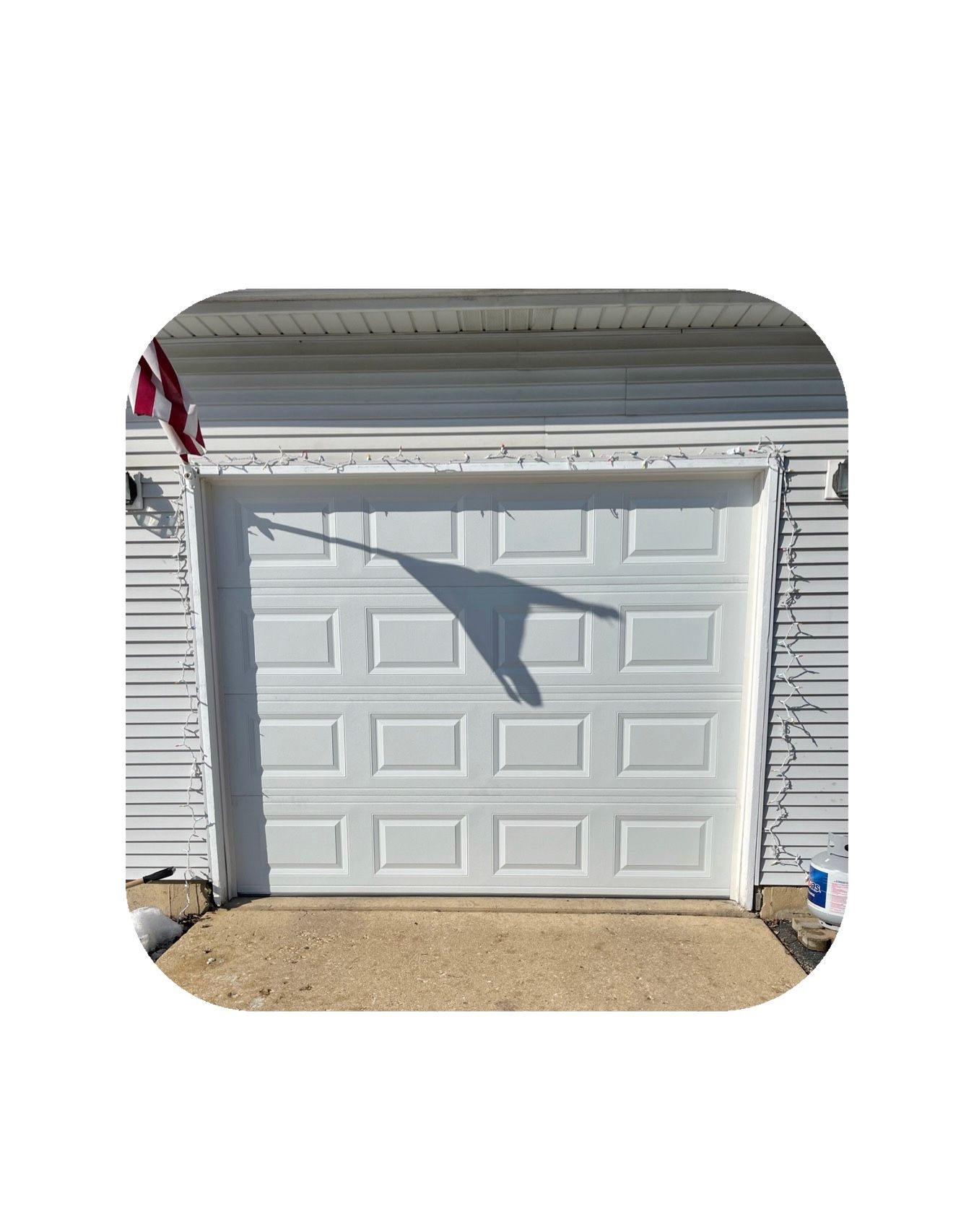 White garage door with shadow of a hanging object on its surface.