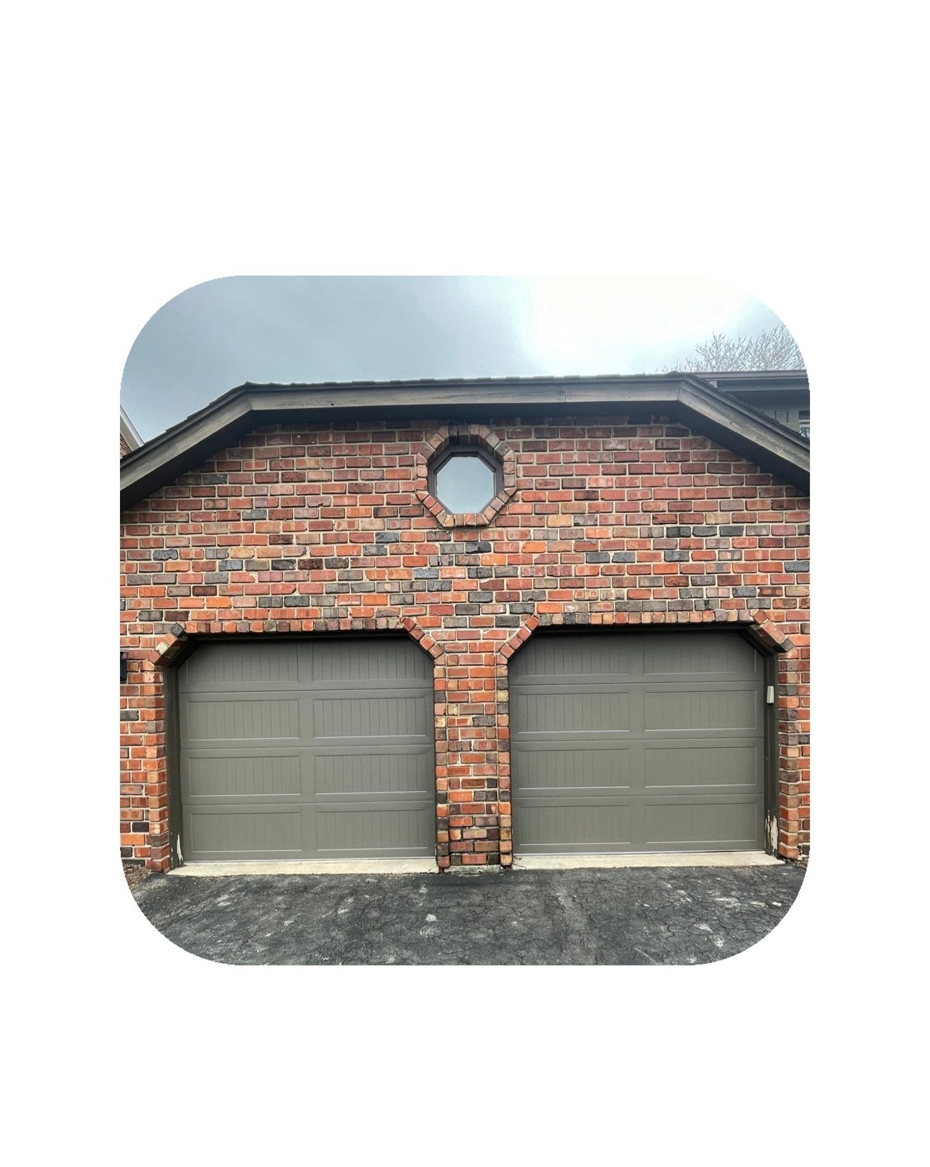 Brick garage with two gray doors and a circular window.