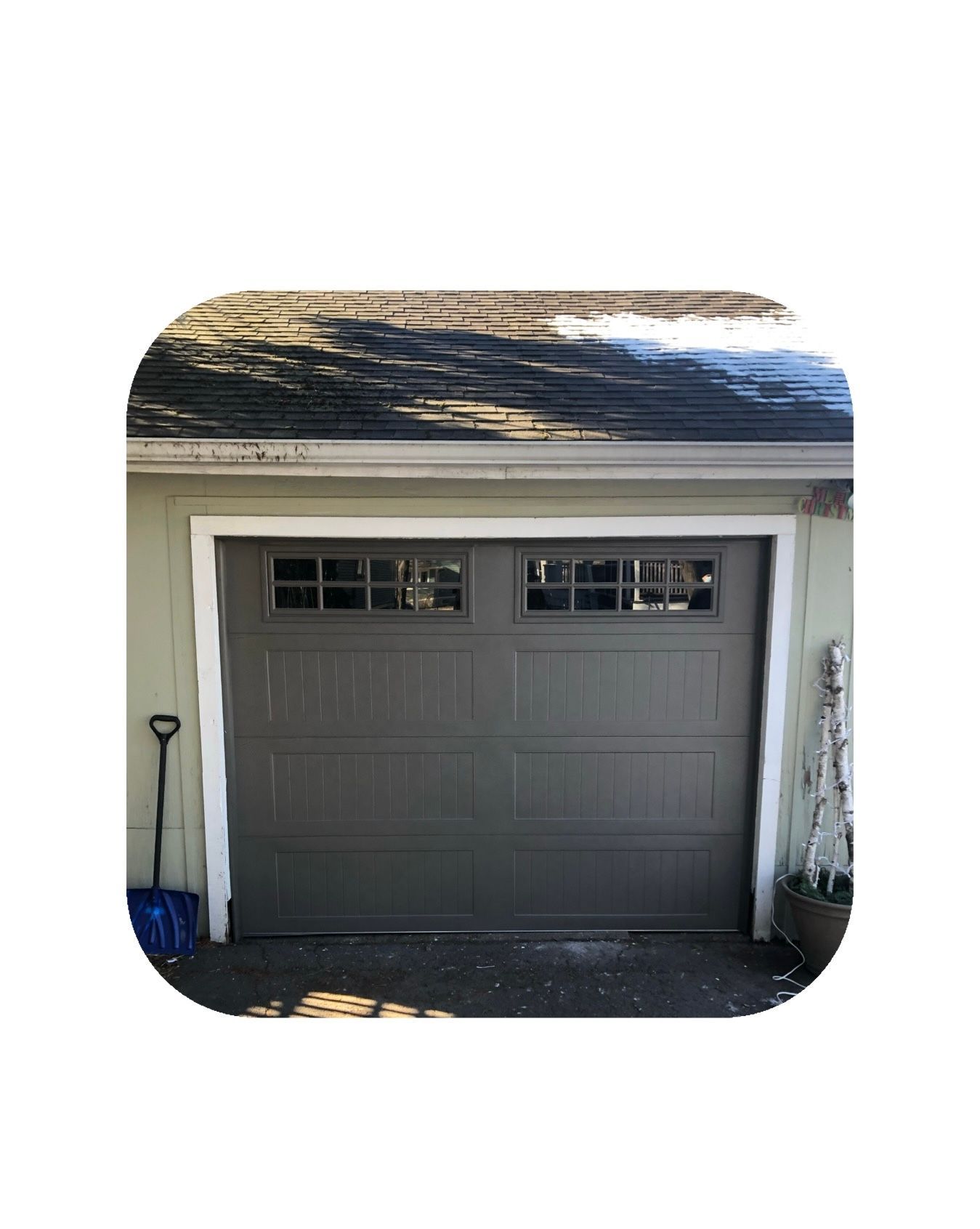Brown garage door with windows, white trim, on a light green building.
