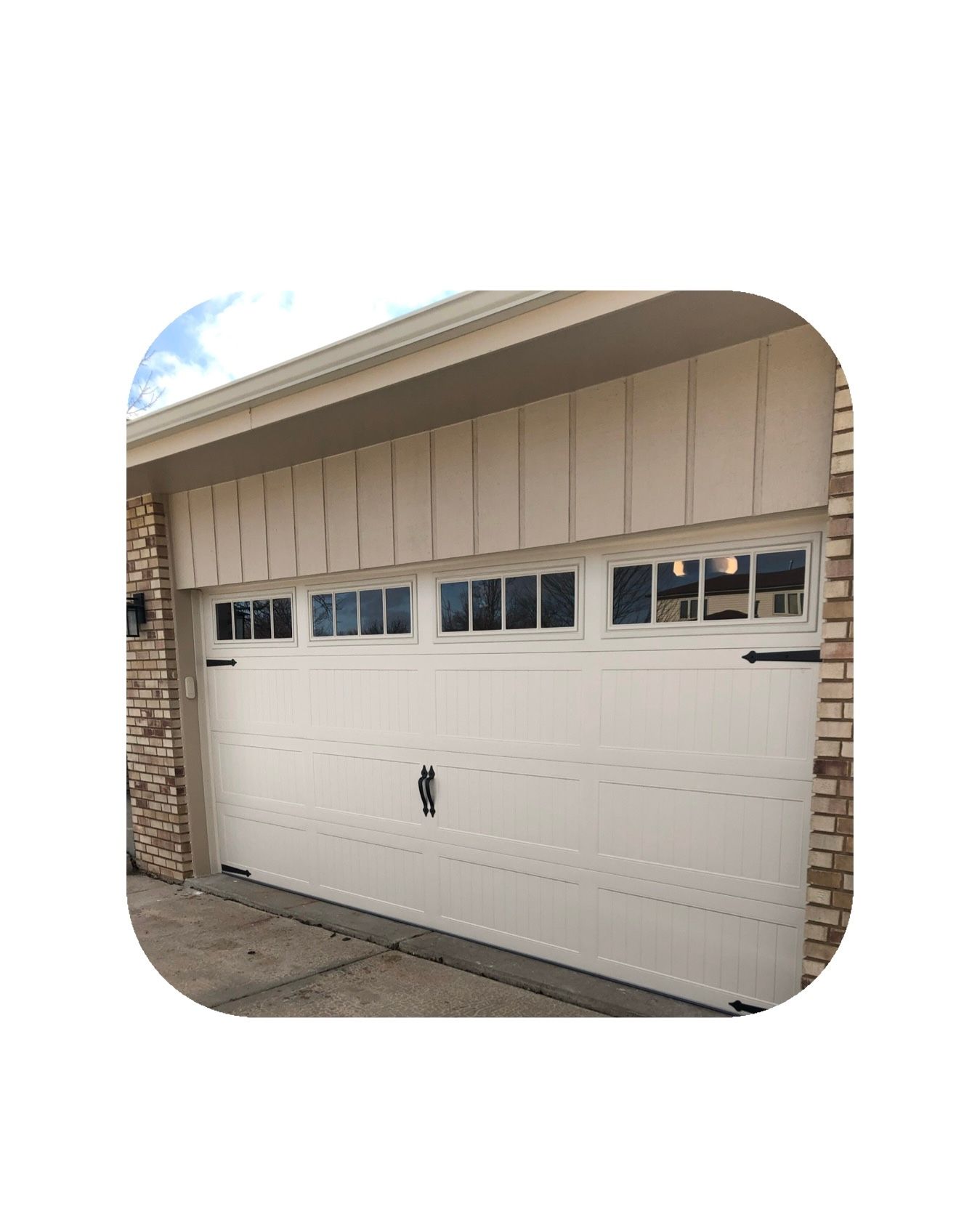 White garage door with windows, tan trim, and brick accents.