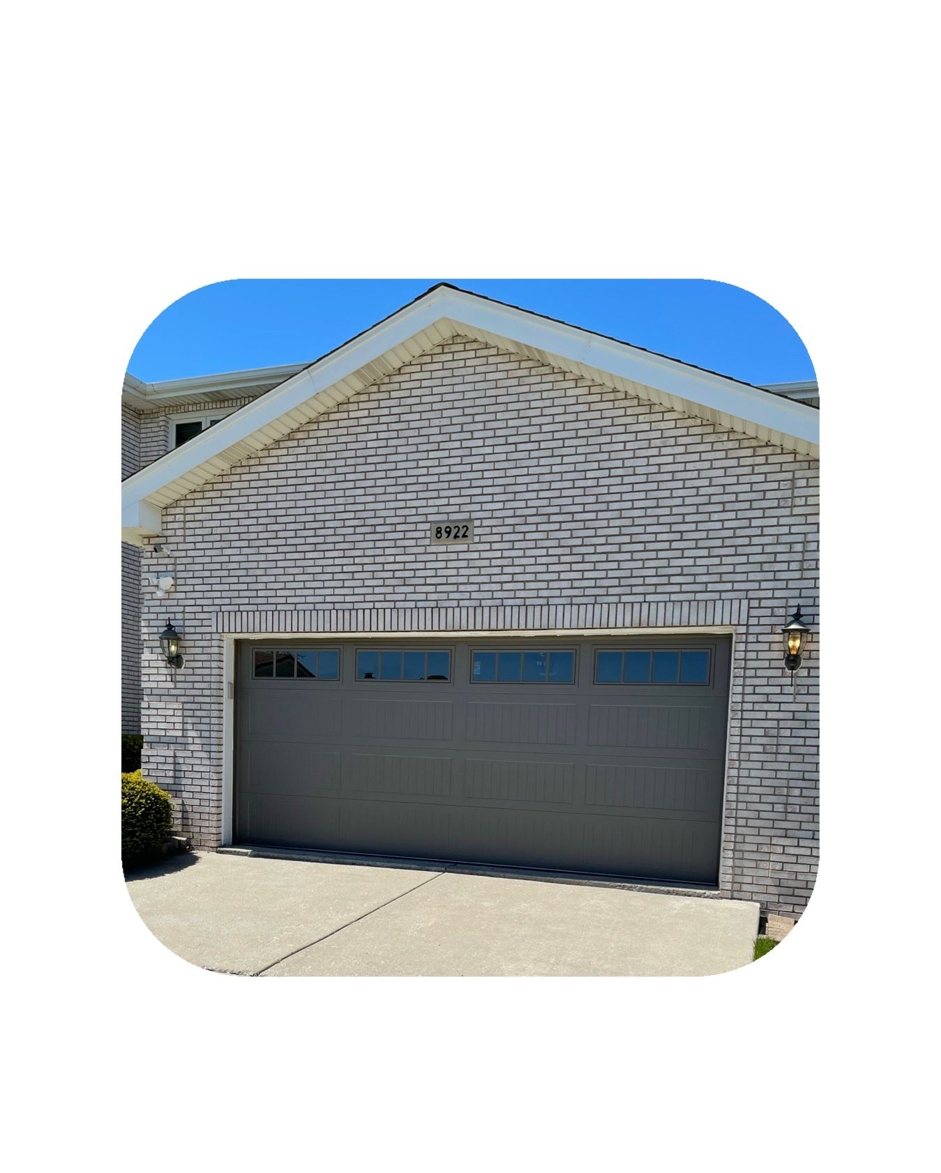 Garage with a gray door and white brick facade.