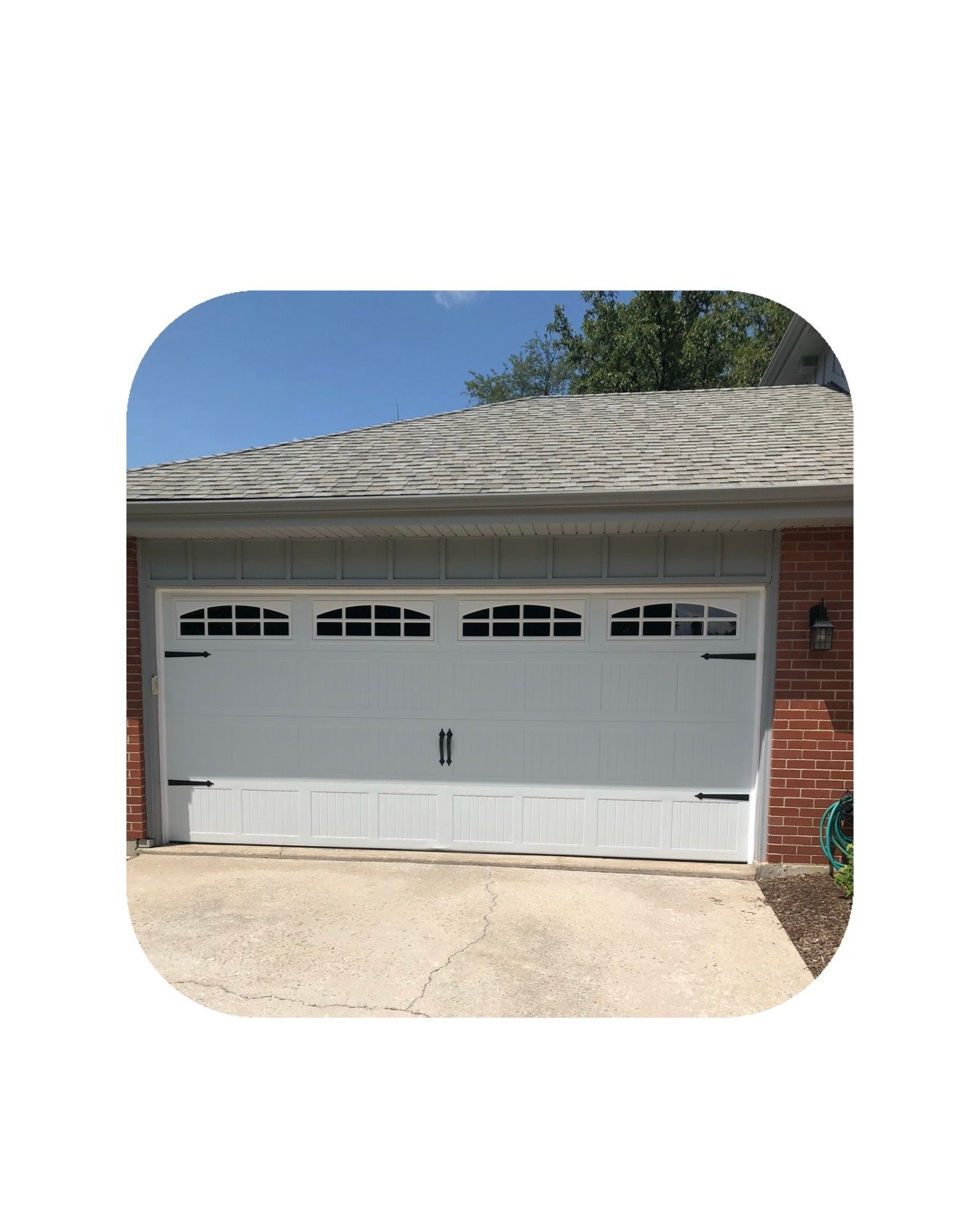 White garage door with windows, on a house with a gray roof.