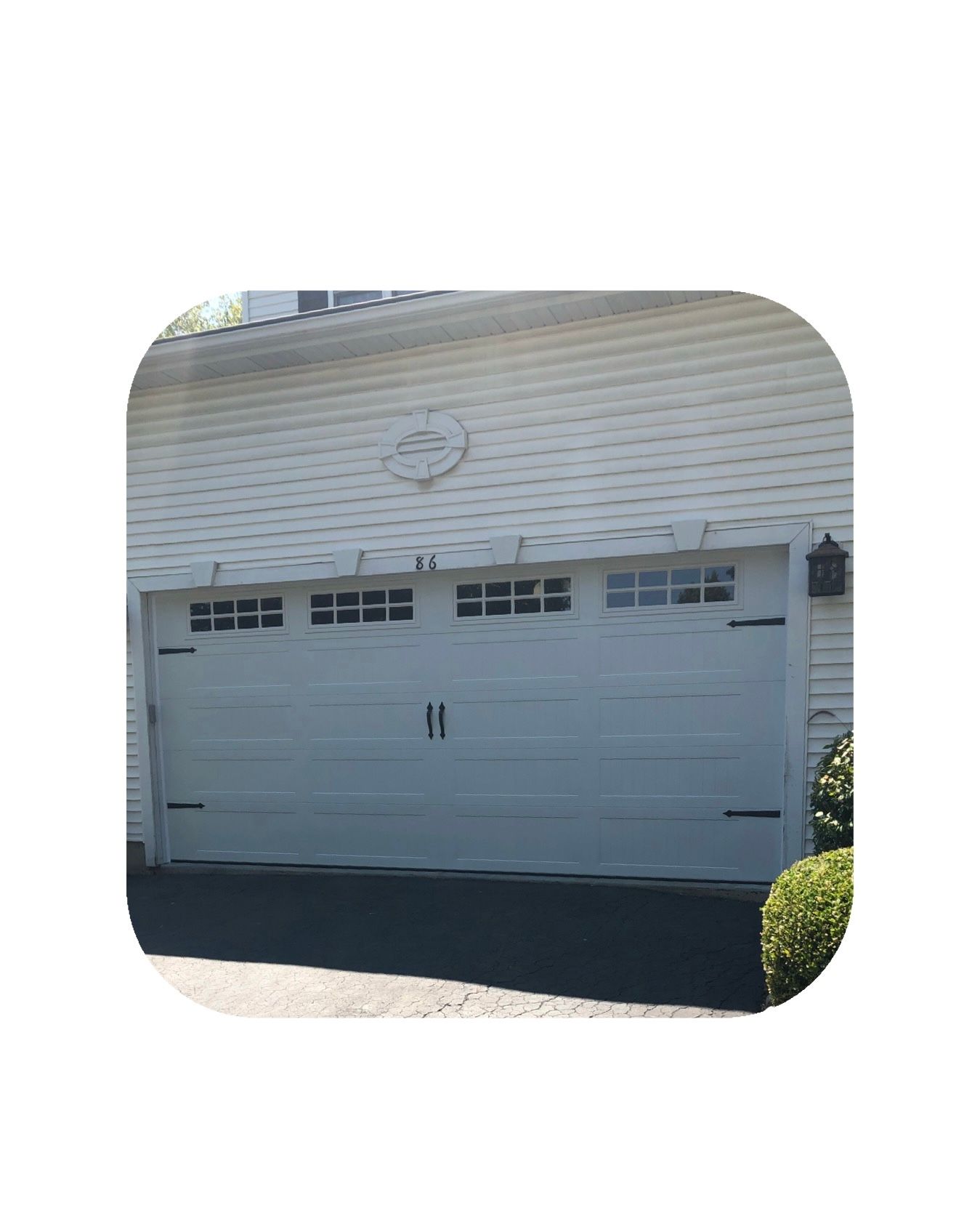 White garage door on a house with decorative black hardware and multiple windows.