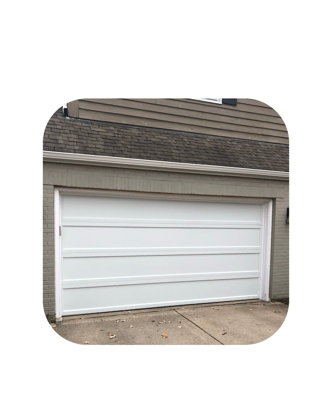 White garage door on a concrete surface, with a brick wall behind it.