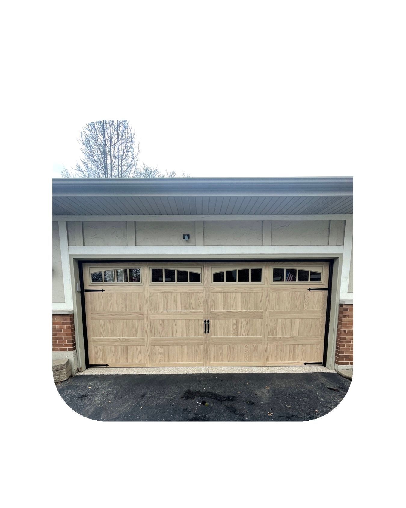 Tan garage door with windows, black hardware, set in a light-colored frame.