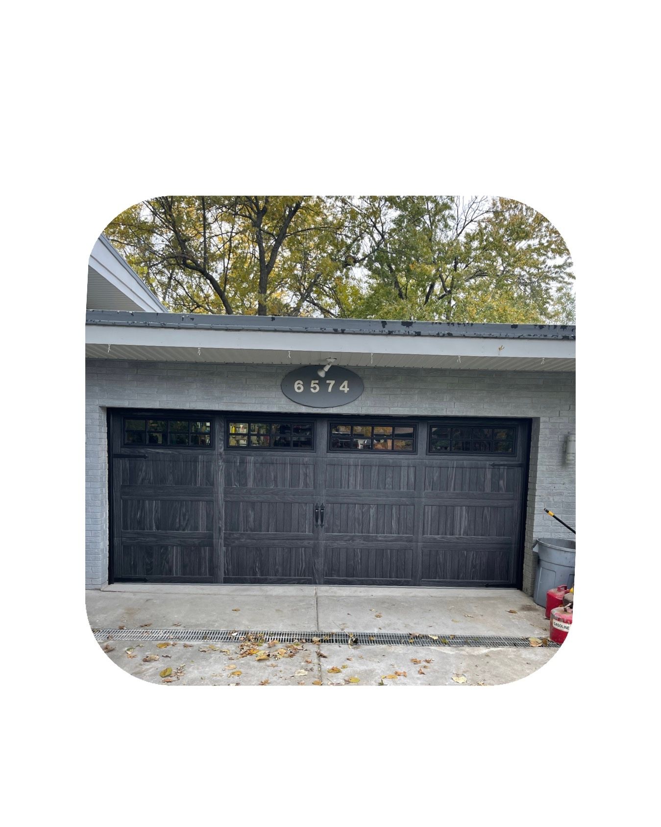 Dark gray garage door with windows and address plaque above.