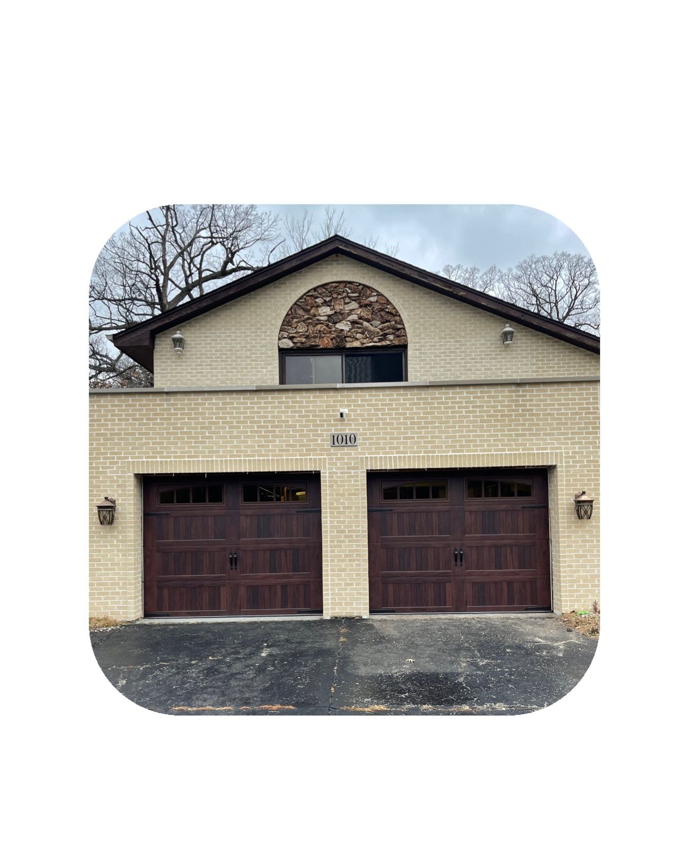 Two-car garage with dark brown doors, tan brick, and an arched section above.