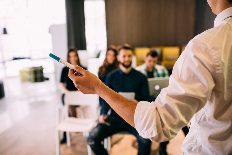 um homem está fazendo uma apresentação para um grupo de pessoas sentadas em cadeiras.