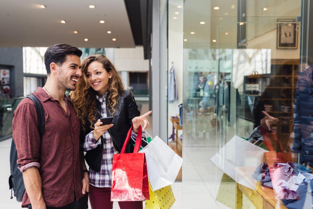 um homem e uma mulher estão olhando a vitrine de uma loja.